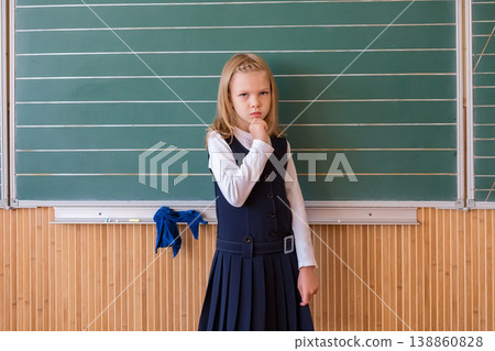 First grade pupil a girl writing on green blackboard at school lesson First grade pupil a girl writing on green blackboard at school lesson 138860828