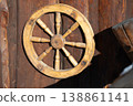wooden wagon wheel leaning against a weathered wooden wall. 138861141