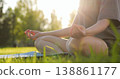 Young woman practices yoga meditation outdoors in park during golden hour. Girl closeup sits in lotus pose green grass sunset. Female lotus position. Healthy lifestyle harmony wellness deep relaxation 138861177