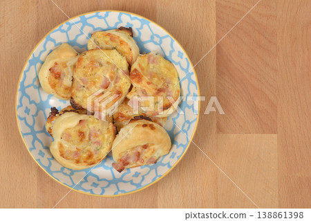 Baked puff pastry rolls with cheese and ham on a plate 138861398