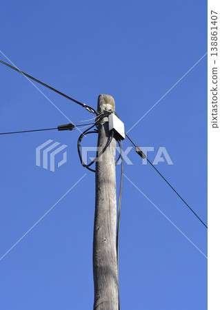Old wooden utility pole with wires against blue sky Old wooden utility pole with wires against blue sky 138861407