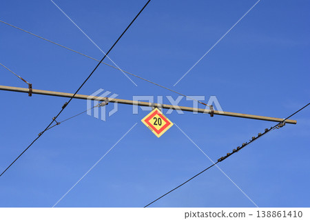 Yellow number twenty speed limit sign on overhead tram wires 138861410