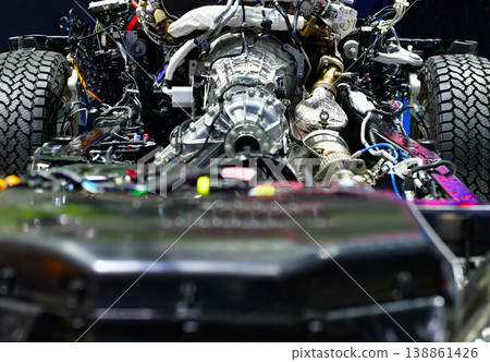 Detailed view of an internal combustion engine and 4x4 drivetrain mounted on a vehicle frame, showing mechanical components. Detailed view of an internal combustion engine and 4x4 drivetrain mounted on a vehicle frame, showing mechanical components. 138861426