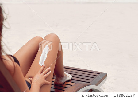 Closeup on female hand applying sunscreen creme on the leg. Skincare. Sun protection sun cream, on her smooth tanned legs. Closeup on female hand applying sunscreen creme on the leg. Skincare. Sun protection sun cream, on her smooth tanned legs. 138862157