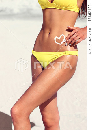 Woman with suntan lotion in form of the heart in yellow bikini Woman with suntan lotion in form of the heart in yellow bikini 138862161