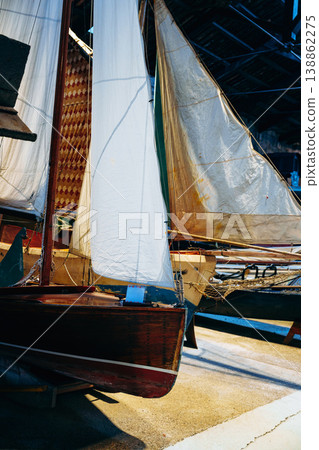 Boats with sails in a dock area during the early evening hours Boats with sails in a dock area during the early evening hours 138862275