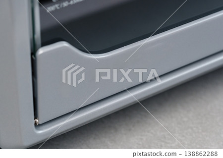 Metallic toaster resting on a kitchen countertop after use, displaying a slightly opened crumb tray at midday 138862288