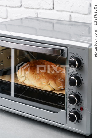 Freshly baked bread rising in a countertop oven during afternoon in a modern kitchen Freshly baked bread rising in a countertop oven during afternoon in a modern kitchen 138862308