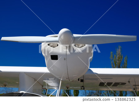 Low angle of white light aircraft wings with propeller spinner against clear blue sky at airfield Low angle of white light aircraft wings with propeller spinner against clear blue sky at airfield 138862325