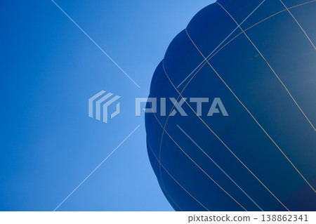 Closeup of dark blue hot air balloon envelope surface with rope lines against clear blue sky outdoor 138862341