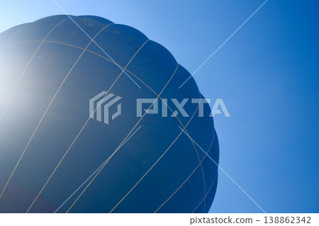 Closeup of dark blue hot air balloon envelope surface with rope lines against blue sky 138862342