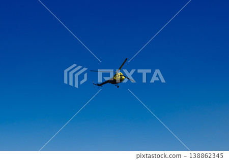 ellow rescue helicopter flying against deep clear blue sky with copy space at outdoor aviation airshow 138862345
