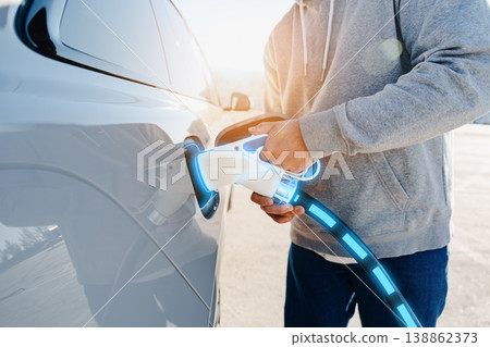 Person charging an electric car at a charging station during daylight 138862373
