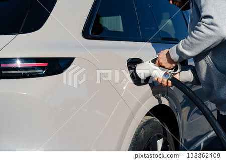 Charging an electric car at a public charging station during the day in a city setting Charging an electric car at a public charging station during the day in a city setting 138862409