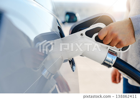 Charging an electric car at a public station during daylight hours Charging an electric car at a public station during daylight hours 138862411