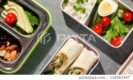 Healthy lunch boxes with vegetables, rice, and wraps on a gray surface 138862447