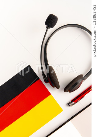 Learning German with headphones, flag, and pen on a table during study time 138862452