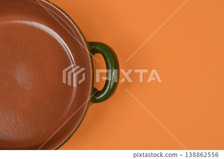 Clay Pot with Green Handle on Orange Clay Pot with Green Handle on Orange 138862556