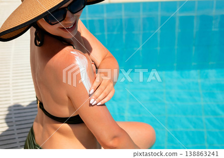 Beautiful Woman Smiling Applying Sunscreen on Shoulder by Pool. Skincare Routine and Summer Concept Beautiful Woman Smiling Applying Sunscreen on Shoulder by Pool. Skincare Routine and Summer Concept 138863241