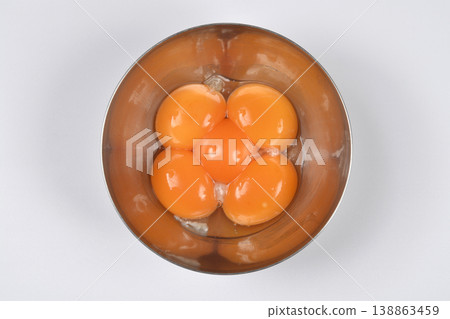 Five raw egg yolks in a stainless steel bowl 138863459