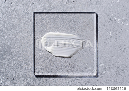 A sample of white body cosmetics on a glass square. Grey background. A sample of white body cosmetics on a glass square. Grey background. 138863526