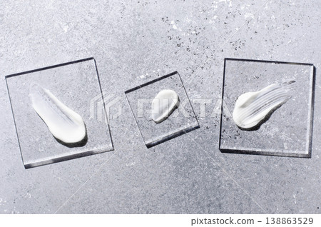 A sample of white body cosmetics on a glass square. Grey background. 138863529