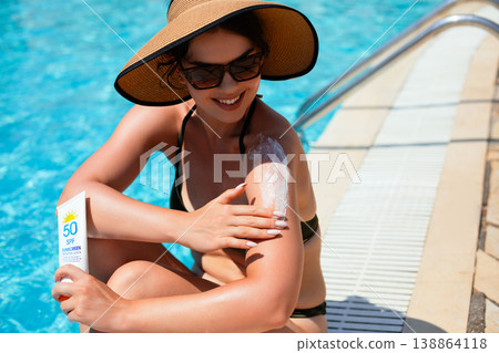 Woman Sitting By Poolside Applying Sunscreen On Shoulder Relaxing In Summer Sunlight. Skincare And Healthy Skin Lifestyle Concept 138864118