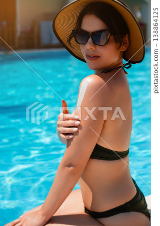 Woman Looking Back With Sunscreen Applied On Shoulder Sitting By Poolside In Summer Sunlight. Skincare And Sun Protection Concept 138864125