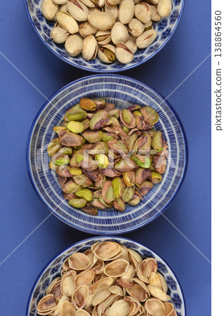 Pistachio varieties in blue bowls on blue background Pistachio varieties in blue bowls on blue background 138864560