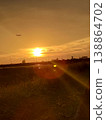 A glorious sunset and a majestic airplane soaring through the sky, visible from the riverbank. 138864702