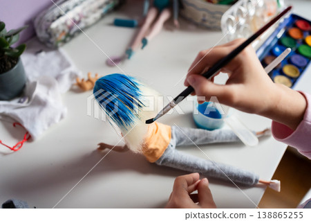 close up kids hands paint dolls hair blue with a brush on a table diy 138865255