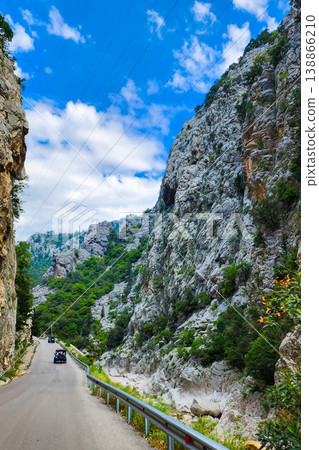 Mountain road winding through a steep canyon with cars Mountain road winding through a steep canyon with cars 138866210