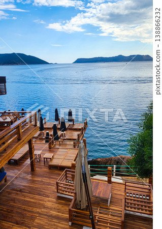 Wooden deck overlooking blue sea with lounge chairs Wooden deck overlooking blue sea with lounge chairs 138866232