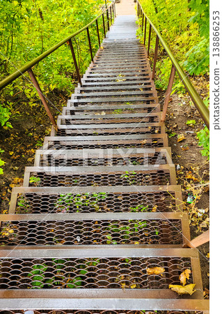 Metal stairs descending into green forest woods Metal stairs descending into green forest woods 138866253