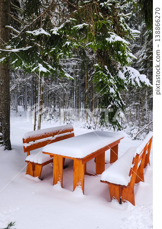 Wooden picnic table covered in fresh snow in forest Wooden picnic table covered in fresh snow in forest 138866270