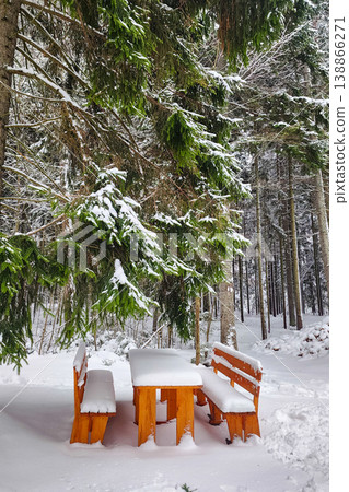 Wooden picnic table covered in fresh snow in forest Wooden picnic table covered in fresh snow in forest 138866271