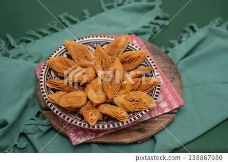Crimean Tatar Baklava, a traditional pastry in bowl. Sweet diamond shapes food green background Crimean Tatar Baklava, a traditional pastry in bowl. Sweet diamond shapes food green background 138867980