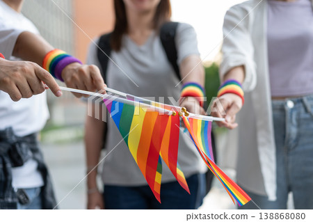 Group of people holding rainbow flags and wearing pride wristbands outdoors. Promotes LGBTQ+ equality, visibility, and community support through vibrant symbols of inclusion and celebration Group of people holding rainbow flags and wearing pride wristbands outdoors. Promotes LGBTQ+ equality, visibility, and community support through vibrant symbols of inclusion and celebration 138868080