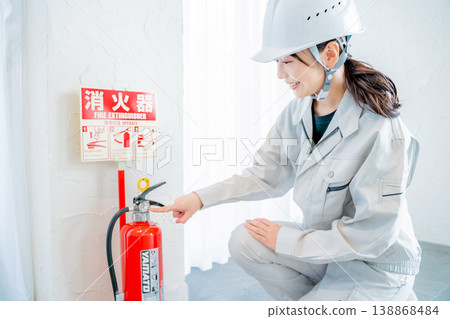 一名身穿工作服的女子正在檢查消防安全設備。 一名身穿工作服的女子正在檢查消防安全設備。 138868484
