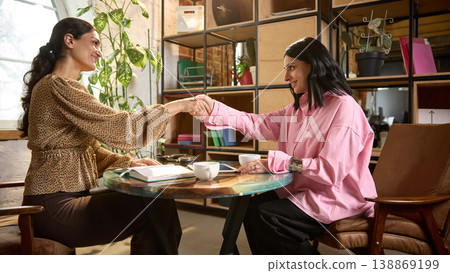 Female business coach shaking hands with woman after successful session. Female business coach shaking hands with woman after successful session. 138869199
