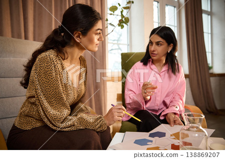 Female business coach guiding woman through project analysis using chart on paper. 138869207