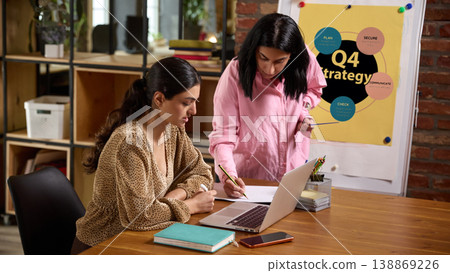 Business coach guiding employee writing notes at laptop during strategy planning meeting Business coach guiding employee writing notes at laptop during strategy planning meeting 138869226