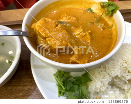 Coconut Chicken Curry - Served with a spoon, cilantro, and rice. Coconut Chicken Curry - Served with a spoon, cilantro, and rice. 138869276