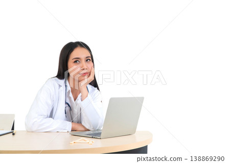 Thoughtful Doctor: A portrait of a focused doctor sitting at a desk with a laptop, looking into the camera. captured the serious and professional atmosphere. 138869290