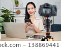 Content Creator at Work: A vibrant young content creator, poised and engaging, expertly utilizes modern tech to craft her work, embodying the essence of modern digital media and communication. 138869441