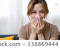 Sneezing During Allergy Season: A young woman, experiencing a sudden sneeze, uses a tissue to contain the discomfort of seasonal allergies. 138869444