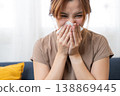 Illness Reflection: A young individual with a look of discomfort, holding a tissue up to their nose. The scene is of health, with a focus on seasonal illness or allergies. 138869445