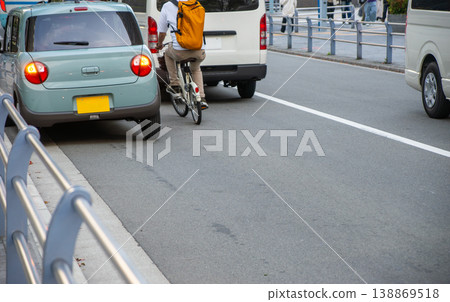 一輛自行車在路上行駛，以避開停放的車輛。 138869518