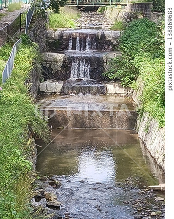 A stone-built drop structure with roses in bloom and a clear stream. A stone-built drop structure with roses in bloom and a clear stream. 138869683