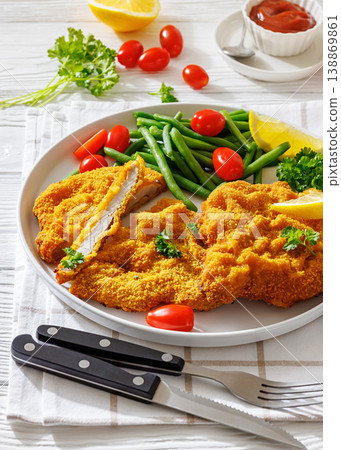 Breaded pork schnitzel with green beans and lemon Breaded pork schnitzel with green beans and lemon 138869861